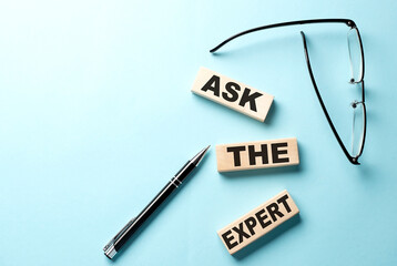 Text ASK THE EXPERT concept on wooden block on the blue background