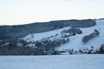 Panoramic view of Einsiedel damm Talsperre in Chemnitz, Saxony, Germany during ice cold winter of Ore Mountains (Erzgebirge) with frozen trees and forests in background. Houses in middle ground.