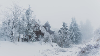 Abandoned mountain chalet in Bozi Dar Czech Republic during icy foggy, winter time in Ore Mountains (Erzgebirge). Mist, snow and fog covering frozen landscape.