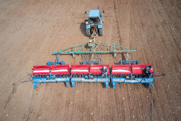 Tractor with a seeder on arable land. Grain and mineral fertilizer are filled into the seeder...