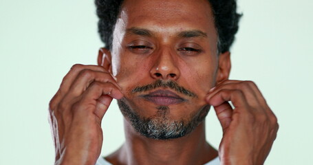 Person massaging his own face close-up. African man touching face relaxing and resting