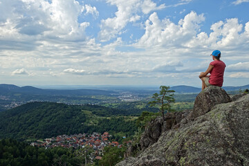 Frau sitzt auf einem Felsen und überblickt den Schwarzwald bei Gernsbach