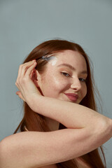 Fototapeta premium Smiling young beautiful ginger girl use eye lift tapes for fox eyes effect, lifting of eyelids and brows, perfect makeup