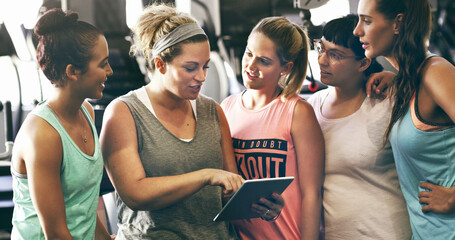 Just download this app.... Cropped shot of a group of young women looking at a digital tablet in the gym.
