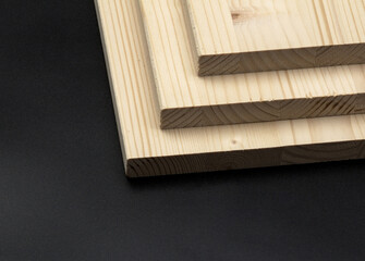 White pine planks, on a black background. Three brown planks stacked on top of each other, in the shape of a triangle.