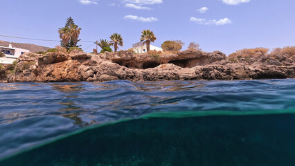 Obraz premium Underwater split photo of small bay and pituresque village of Avlemonas with emerald crystal clear sea in island of Kythira, Ionian, Greece