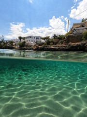 Underwater split photo of small bay and pituresque village of Avlemonas with emerald crystal clear sea in island of Kythira, Ionian, Greece