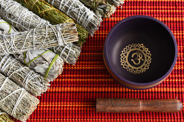 A top view image of several types of smudge sticks with a purple meditation singing bowl.  