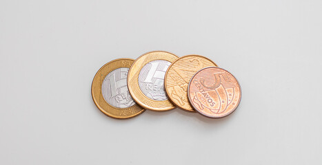Moedas do Real Brasileiro - BRL sobre uma superfície branca. Conceitos de economia brasileira e...