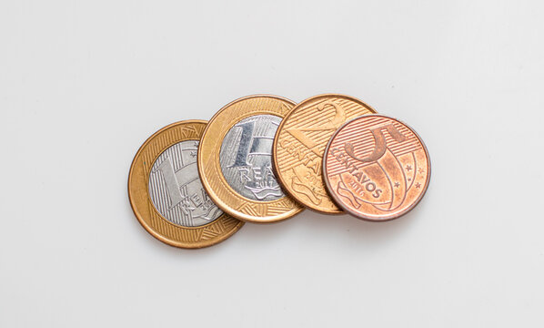 Moedas do Real Brasileiro - BRL sobre uma superf&iacute;cie branca. Conceitos de economia brasileira e finan&ccedil;as.