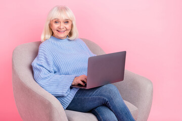 Naklejka premium Portrait of attractive cheerful grey-haired woman using laptop watching movie film isolated over pink pastel color background