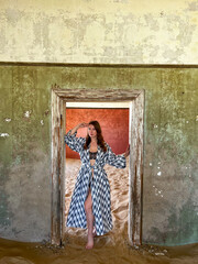 Young woman in dress and underwear in abandoned building posing in room.