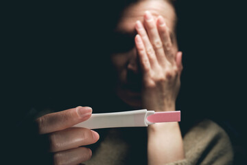 A woman sees a positive pregnancy test result and feels fear.