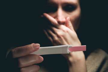 A woman sees a positive pregnancy test result and feels fear.