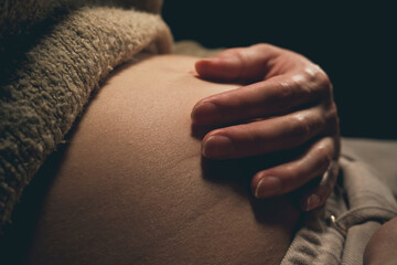 Pregnant woman touching her hand to her belly.