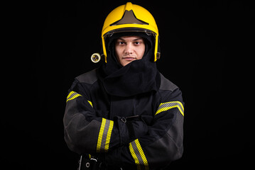Fototapeta premium Firefighter fully equipped with helmet and ax in smoke, black background