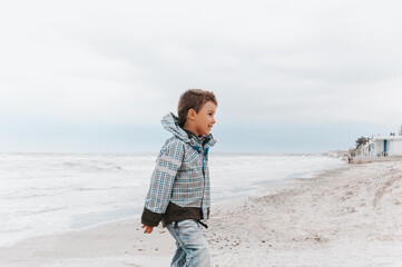 portrait of a attractive handsome smiling boy in a vest. Funny cute child in summer by stormy sea weather. Happy childhood.