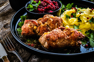 Wrapped pork with potato puree and red beets on wooden table
