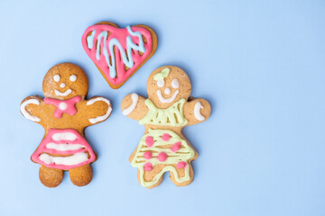 Black and white homosexual couple, two gingerbread girls and heart on the blue background with copy space for St Valentines Day. 