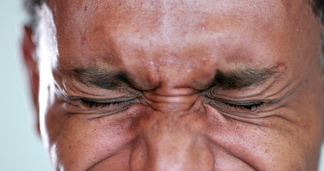 African man eyes squinting. Close-up black guy closing eyes squint
