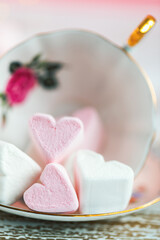 Obraz na płótnie Canvas Heart-shaped marshmallows in an overturned porcelain teacup. Soft focus.