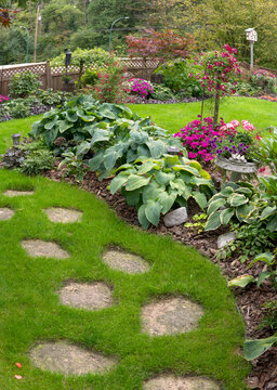 Path and stepping stones leading to a beautiful floral and green garden.
