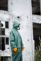 A dosimetrist scientist in protective clothing and a gas mask checks the level of radioactive...