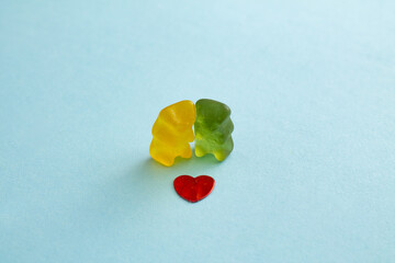 Colorful jelly gummy bears and red heart on blue background. Valentine day composition. Minimalism. 