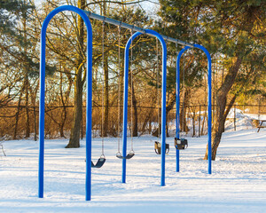 Fototapeta premium Children's swings with park with snow