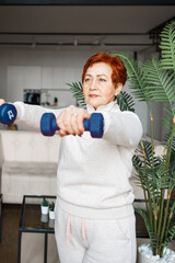 Older Caucasian woman works out with dumbbells at home