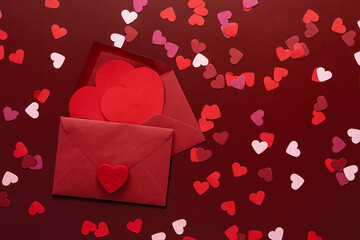 Craft envelope with a blank sheet of paper inside and red heart on the red background. Romantic love letter for the Valentine's day concept. Space for text.