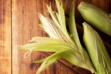 Top view image of raw white corn on the cob on wooden rustic surface. Flat Lay with copy space.