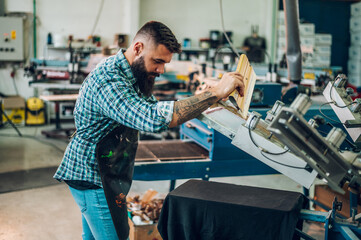 Male worker using printing machine in a workshop