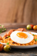 Fried rice with chicken, sausage and fried egg on wooden table