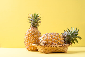 Fresh pineapple fruit in basket on yellow background, Tropical fruit