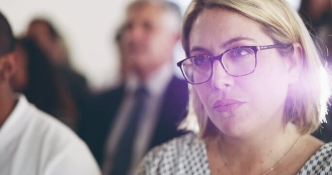 Connecting with the content of the conference. Young business woman sitting at a conference with a group and listening to briefing. Serious woman showing interest at a meeting in a modern office