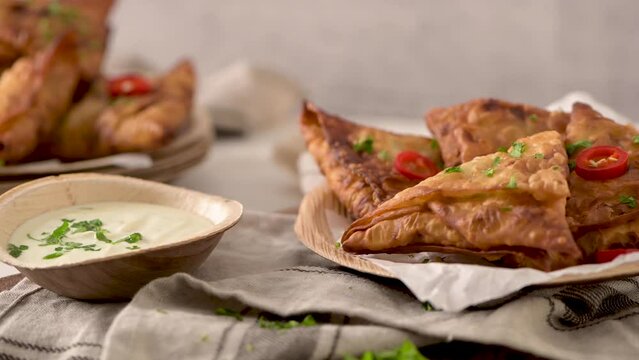 Indian samosas  - fried or baked pastry with savoury filling, popular Indian snacks, served in areca leaf dishes with spices on kitchen countertop.