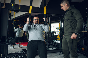Middle aged men with fitness trainer exercising at the gym
