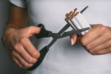 Woman cutting with scissors cigarettes. Stop smoking, quit smoking or no smoking concept. Woman...