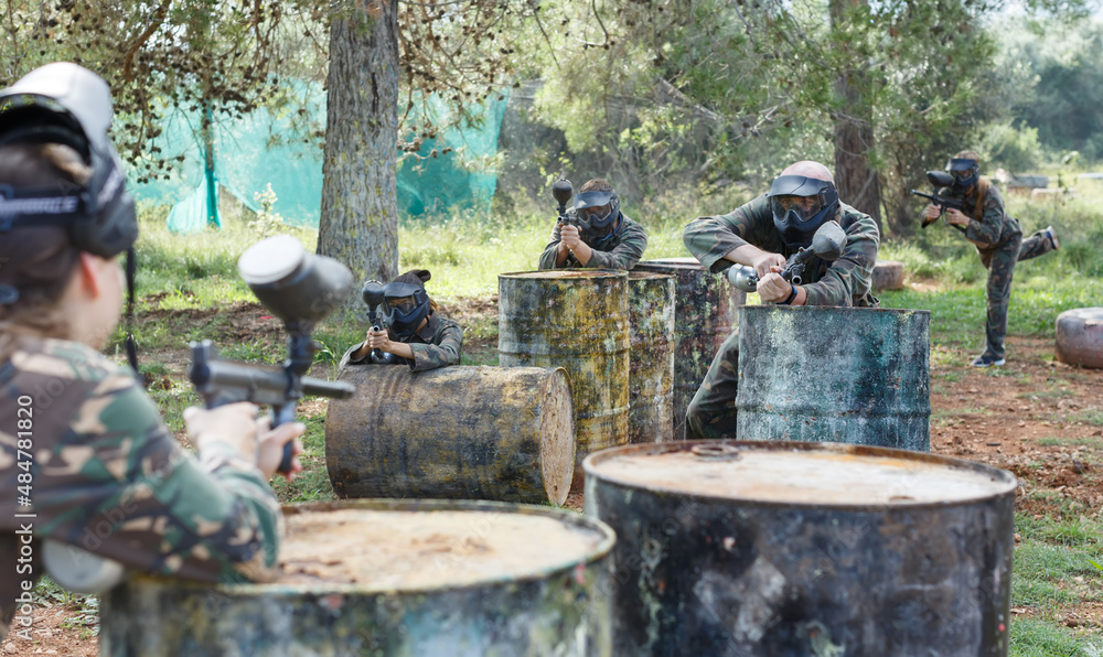 Poster Two opposing teams in camouflage playing paintball against each other in forest