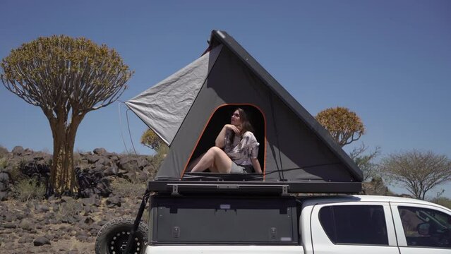 SUV car with camping equipment, rooftop tent, spare tire. Quiver tree forest.