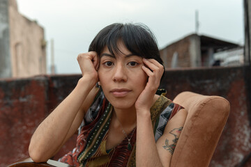 Mujer mexicana con mirada fija sentada en silla en azotea de edificio viejo