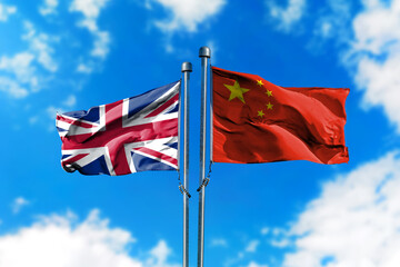 Flags of United Kingdom and China on the wind against blue sky