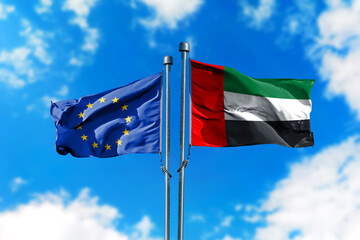 Flags of European Union and United Arab Emirates on the wind against blue sky