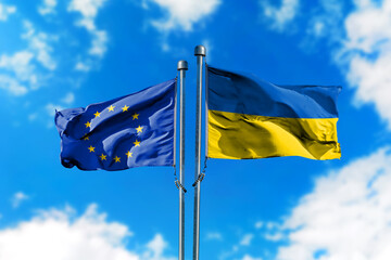 Flags of European Union and Ukraine on the wind against blue sky