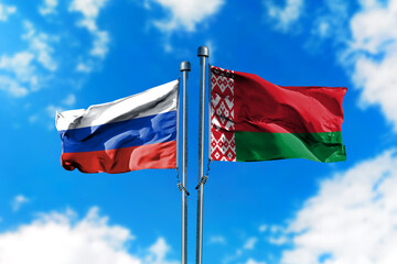 Flags of Russia and Belarus on the wind against blue sky
