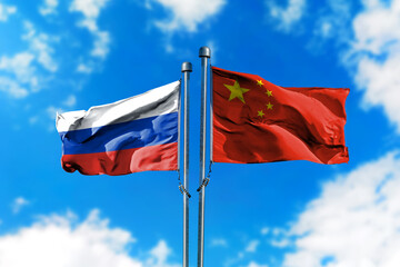 Flags of Russia and China on the wind against blue sky