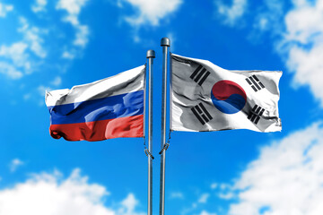 Flags of Russia and South Korea on the wind against blue sky