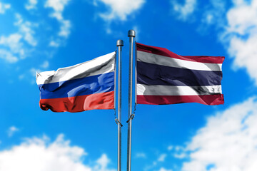 Flags of Russia and Thailand on the wind against blue sky