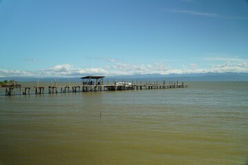 Fototapeta na wymiar Wooden bridge by the sea, clear water and blue sky.